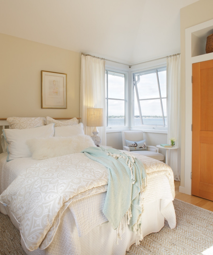aménagement chambre avec vue sur mer, grand lit couvert de coussins et plaid beige et blanc, déco blanc et beige pour une ambiance relaxante