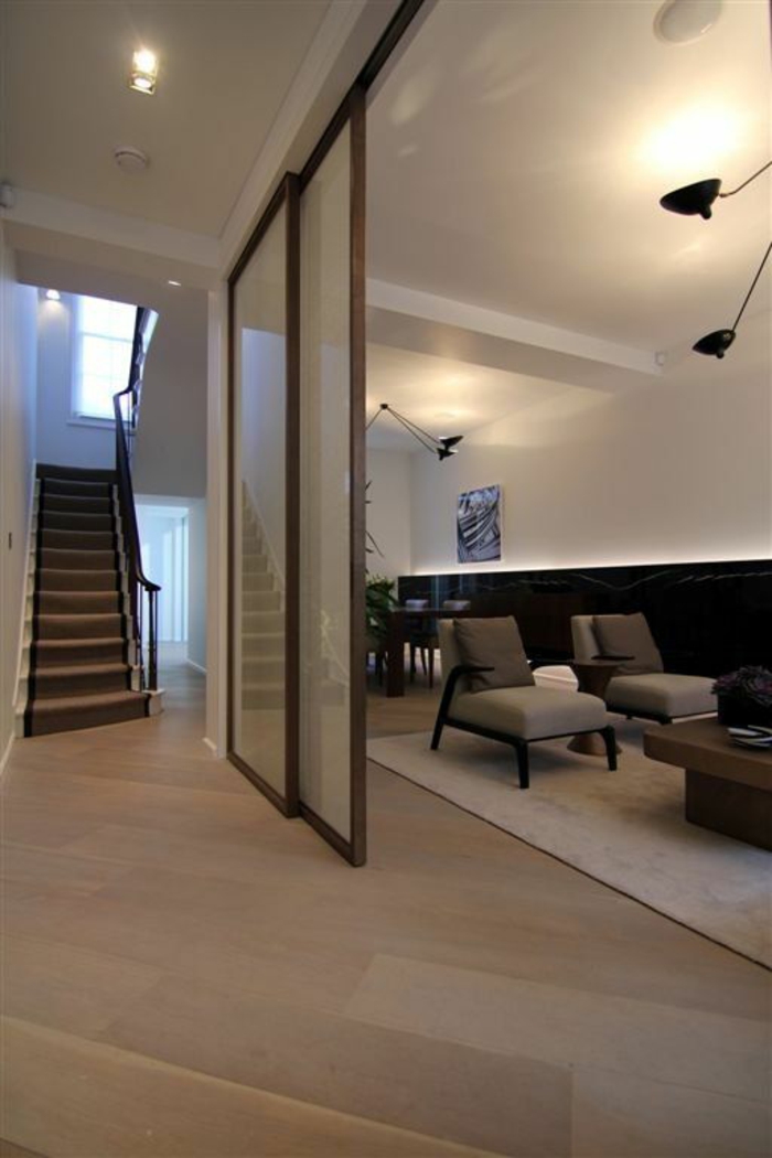 séparation chambre salon escalier, grand espace, plafond blanc, sol recouvert en parquet beige-marron, grand tapis blanc carré