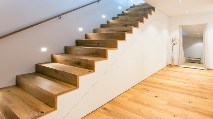 design moderne aux murs blancs et plancher de bois avec un aménagement sous escalier aux portes sans poignées