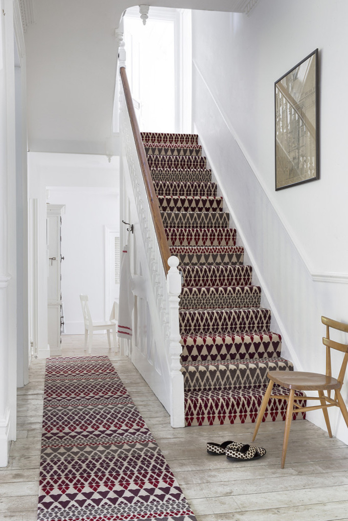 tapis d'escalier à motifs ethnique qui réchauffe la cage d'escalier monochrome aux murs et au lambris peint en blanc