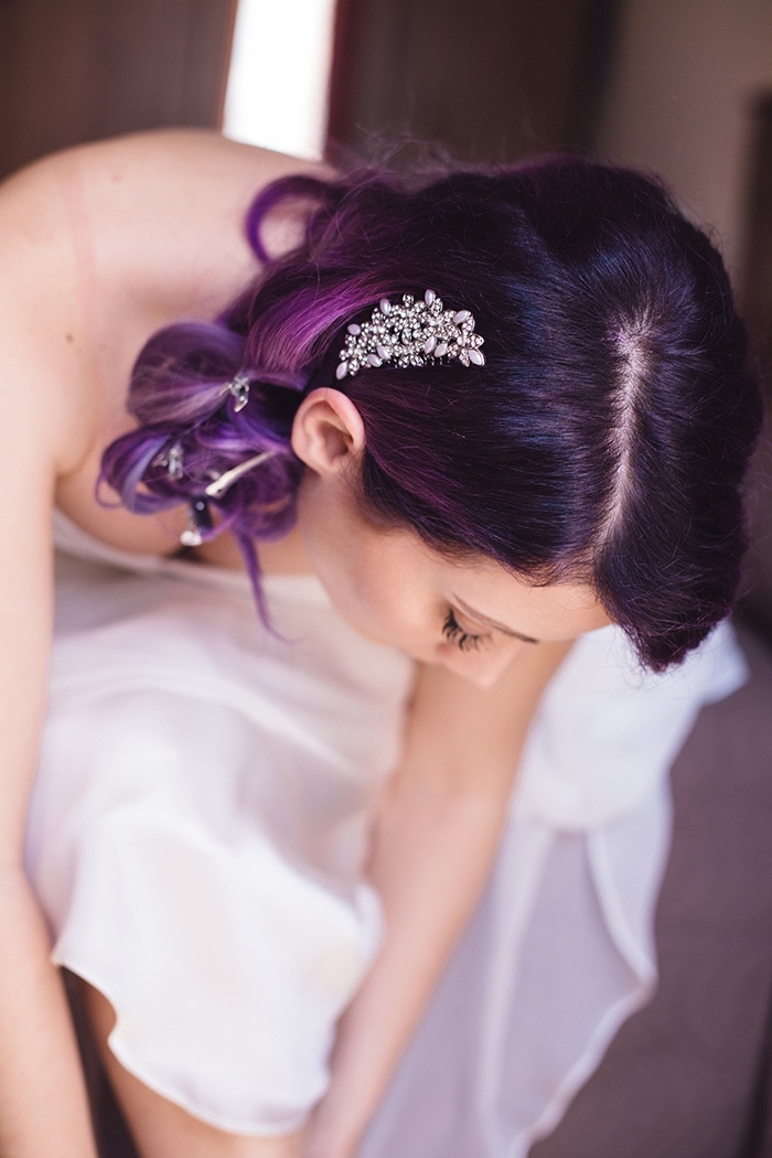 coiffure de mariée aux cheveux longs et bouclés attachés de côté, cheveux aux racines noires et pointes colorés de nuance violet et rose pastel