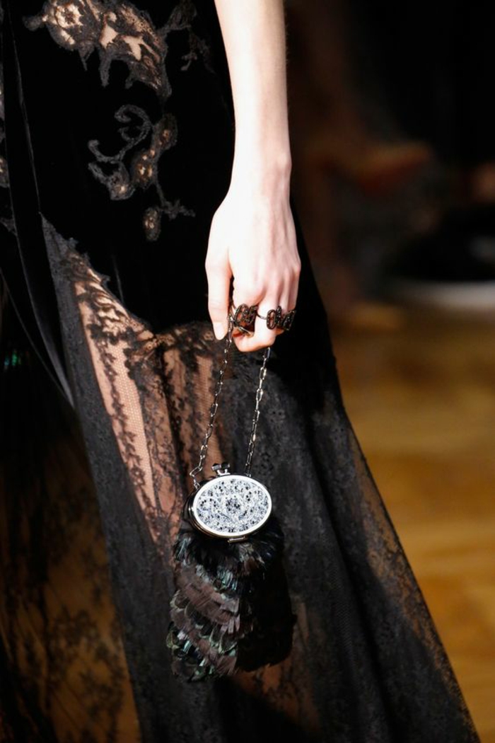 robe de soirée en dentelle noire, avec des arabesques sur la taille, mini bourse style vintage en plumes et grand fermoir en argent, thème chic et choc