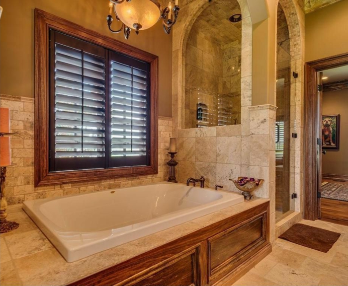 murs en couleur ocre, salle de bain en travertin, luminaire magnifique, petite cabine de douche en pierre
