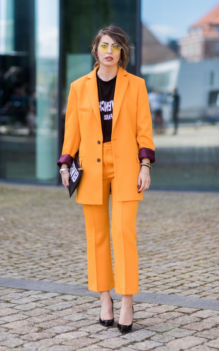 un tailleur pantalon femme de couleur orange tangerine et de coupe masculine, veste structurée combinée avec un t-shirt graphique pour une allure assurée