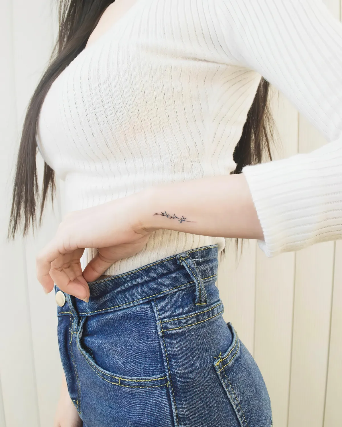 tatouage lettrage sur le poignet femme en top blanc et jeans