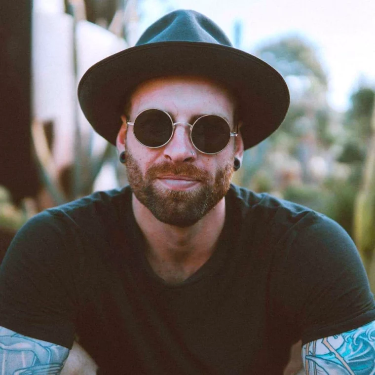 tendance barbe courte 2025 homme avec un chapeau et des lunettes rondes