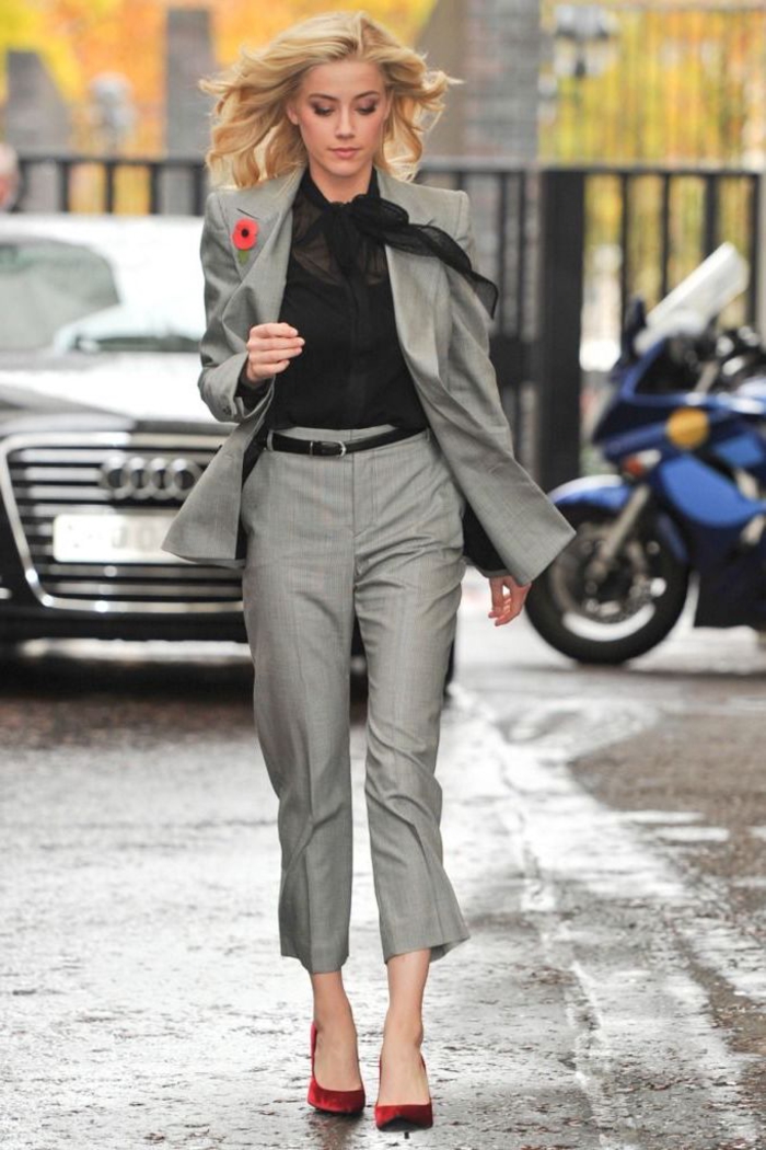 un tailleur pantalon femme gris féminisé par une chemise en voile à col noeud et un petit accent floral au revers