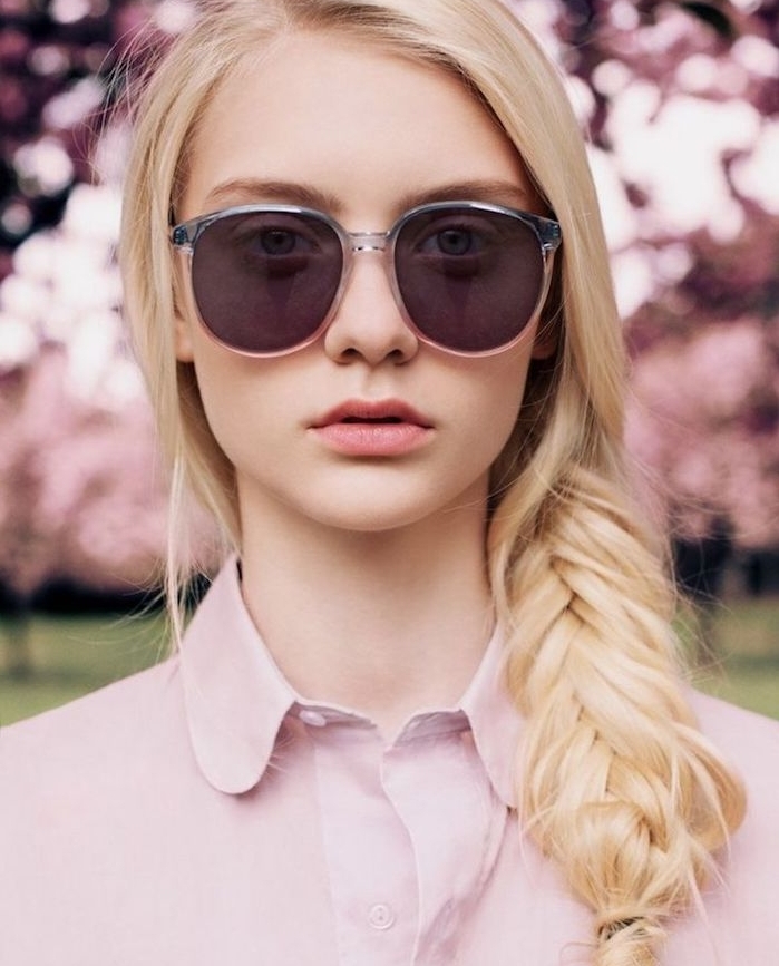 coiffure natte de coté avec des meches libres style décoiffé, chemise femme rose, lunettes de soleil