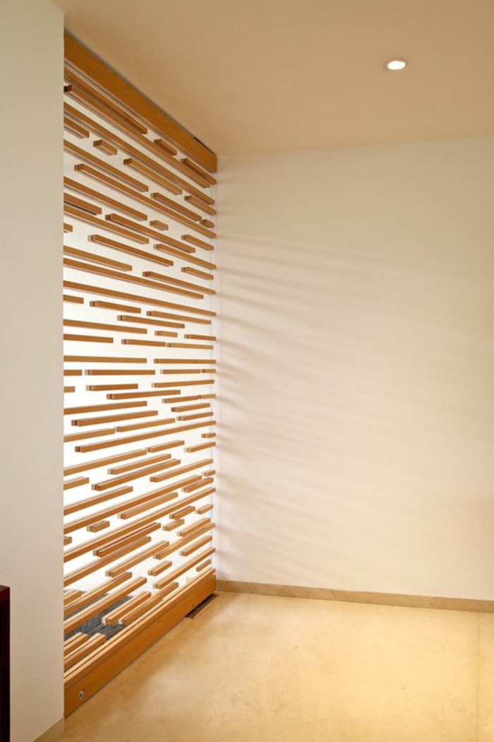 panneau en bois, avec des larges ouvertures pour la lumière, séparation chambre salon, style arty, sol recouvert de parquet clair en PVC 