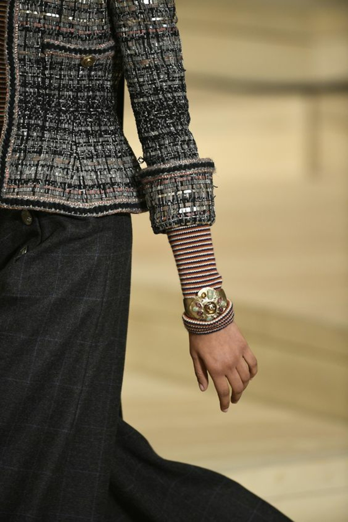 veste en gris, noir et blanc de Chanel, avec jupe grise, manches pliées laissant entrevoir des manches aux rayures rouges et blanches, haut chic bas choc 