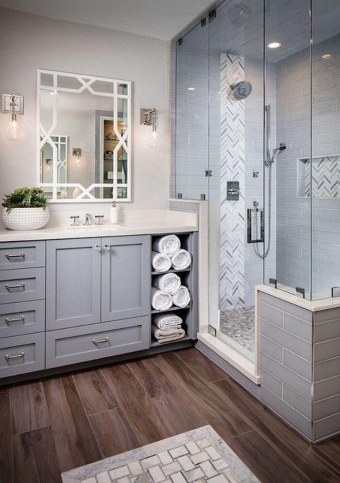 modele salle de bain, salle de bain italienne petite surface, parquet en PVC couleur marron foncé, meuble en bleu pastel, miroir au cadre en blanc orné de motifs graphiques, tapis de bain en blanc et mauve