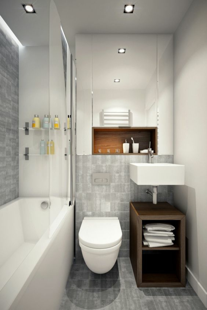 agencement salle de bain, carrelage mural et carrelage du sol en gris clair, meuble lavabo en marron, grande baignoire blanche rectangulaire