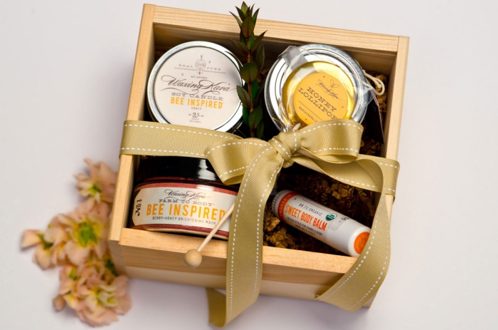 collection de produits naturels bio dans une boîte de bois avec un emballage en ruban doré, bocaux de miel bio naturel