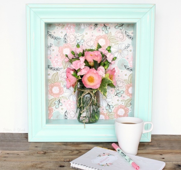 cadre repeint de peinture bleue sur un fond en tissu à imprimé floral et un pot en verre avec un bouquet de fleurs à l intérieur, idée d activité manuelle, deco printemps originale à effet 3d