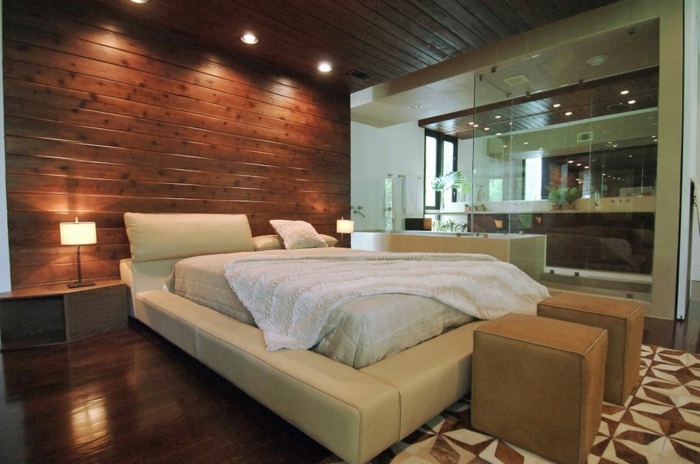 revêtement mural planches de bois, encadrement de lit en cuir beige, tapis géométrique, sol en bois