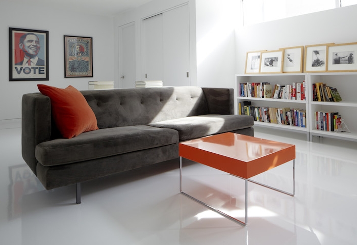 association de couleur avec le gris, canapé couleur gris anthracite, table basse et coussin décoratif orange, murs, sol et etagere blanc