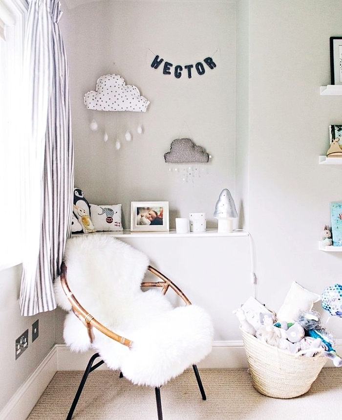 accessoires cozy dans la chambre bébé fille aux murs blancs avec objets décoratifs blancs et chaise papillon à housse blanche
