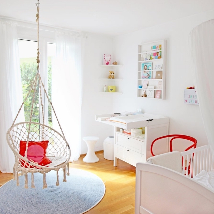 deco chambre bebe aux murs blancs et parquet de bois clair avec chaise suspendue et table à langer de bois blanc