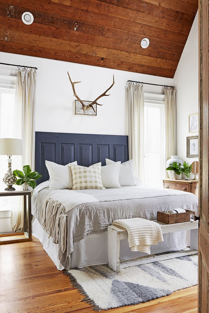 une chambre à coucher aménagée en style campagne chic avec un accent sur les textiles de luxe et tête de lit en bois récup, idée originale pour faire une tete de lit à partir d'une porte ancienne