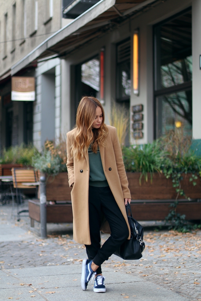vision chic urbain en pantalon noir slim et blouse vert foncé combiné avec un manteau long élégant de nuance beige