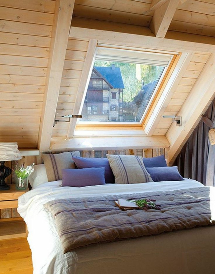 comble aménagé, plafond en bois, lit avec plusieurs coussins, fenêtre en pente