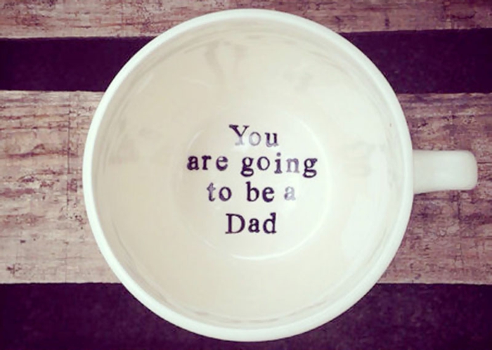 tu seras un père ou comment annoncer une grossesse, une tasse blanche avec un script au fond