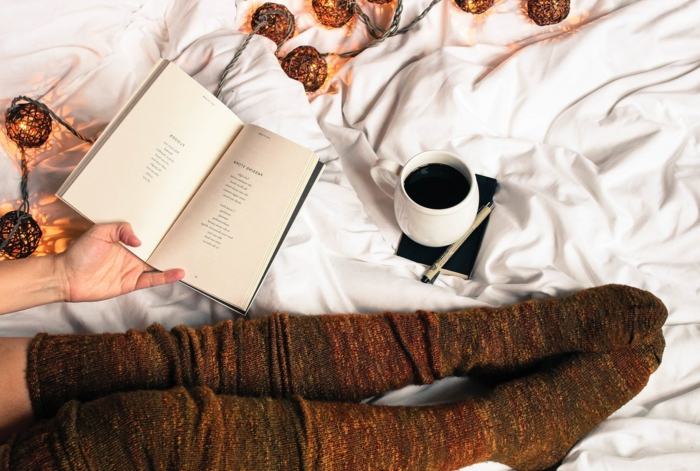chaussettes marrons hautes, guirlande cocooning, tasse de café, livre de poésie
