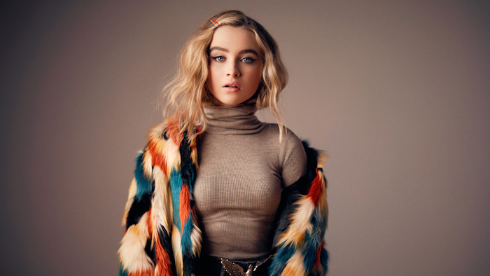 idée de coupe ado carré long blond avec des boucles légères, pull marron et veste colorée