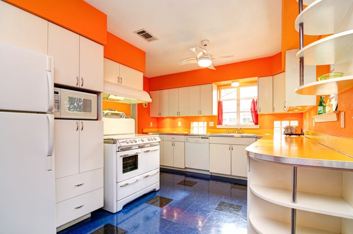 repeindre cuisine, murs en orange flambant, meubles en blanc, carrelage en dalles en bleu royal et noir, plafond en blanc avec luminaire ventilateur 