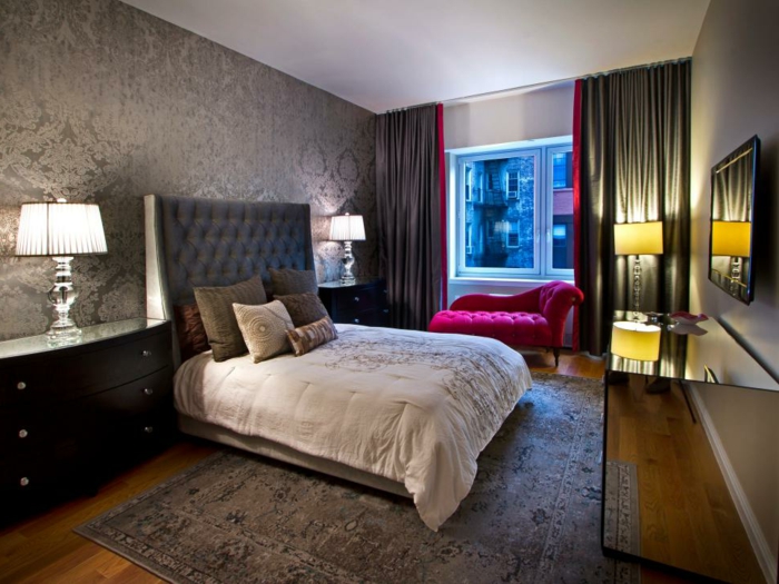tapis gris dans une belle chambre à coucher, sofa rose, lampes abat-jours, tete de lit grise 