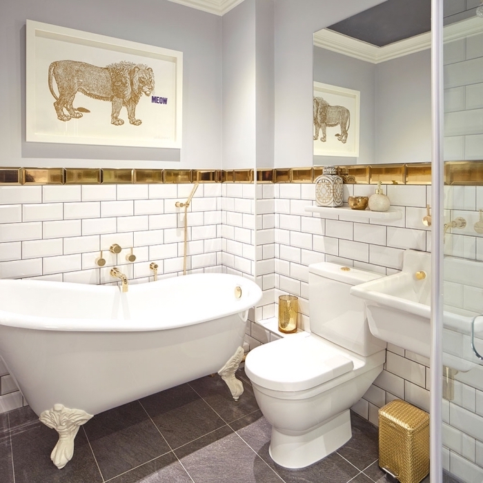 salle de bain moderne aux éléments traditionnels avec un revêtement mural de carrelage à imitation briques blanc et or, baignoire blanche autonome sur plancher gris 