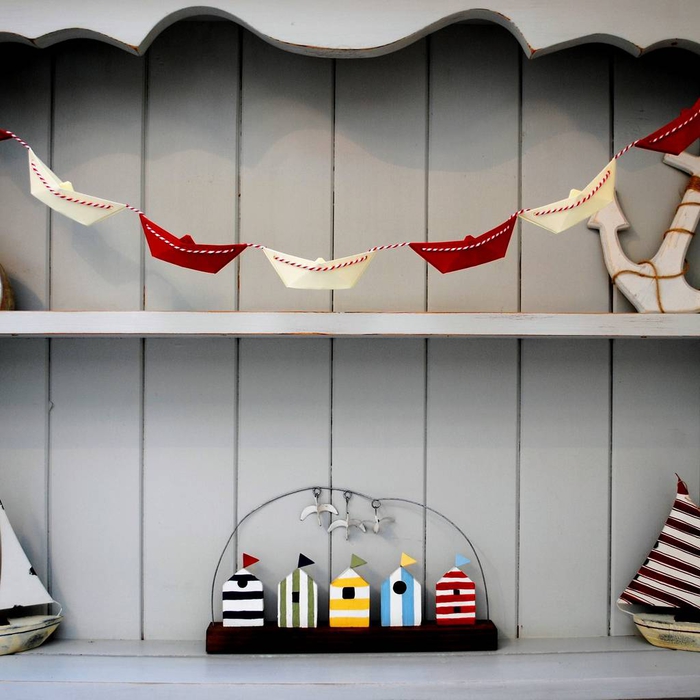 idée originale pour une déco origami destinée la chambre d enfant, jolie guirlande en bateaux rouge et blanc sur un fond en bois gris