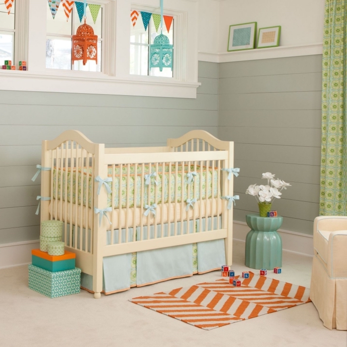 comment combiner les couleurs vert et orange dans la chambre bébé unisexe avec lit à barreaux beige et fauteuil beige