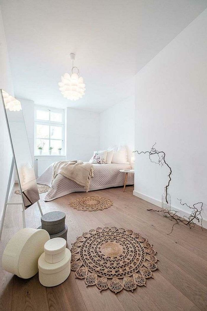 petit tapis boho, sol en planches de bois, murs blancs, plafonnier à plusieurs lamelles, miroir autoportant