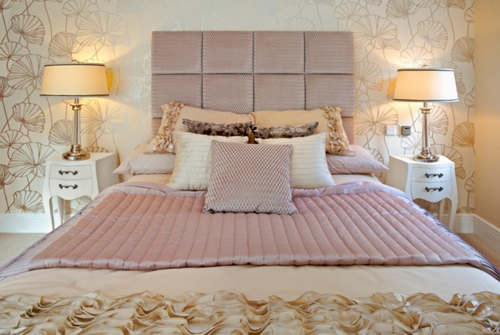 deux lampes abat-jour, lit avec parure couleur rose cendré, papier peint doux en blanc, chambre féminine coquette