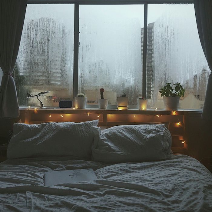 ambiance tamisée dans une chambre romantique, linge de lit blanc, tete de lit en palette avec décoration de guirlande lumineuse