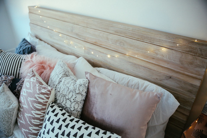 idée simple pour fabriquer une tete de lit en bois avec decoration en guirlande lumineuse, multitude de coussins deçoratifs en rose, blanc, noir et gris pour une ambiance cocooning