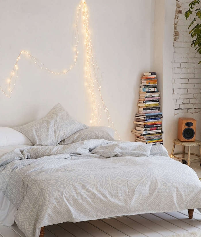 les astuces pour faire une tete de lit, version lumineuse, linge de lit gris et blanc, parquet blanchi, pile de livres, mur en briques blanches apparente
