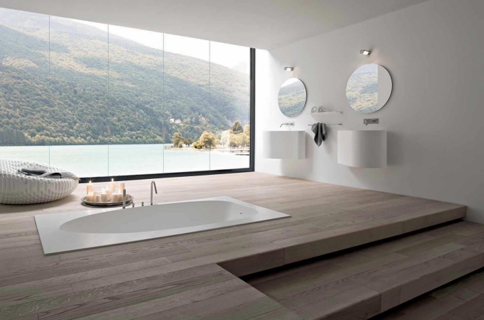 aménagement de la salle de bain spacieuse avec grande fenêtre, baignoire blanche incrustée dans le sol de bois clair