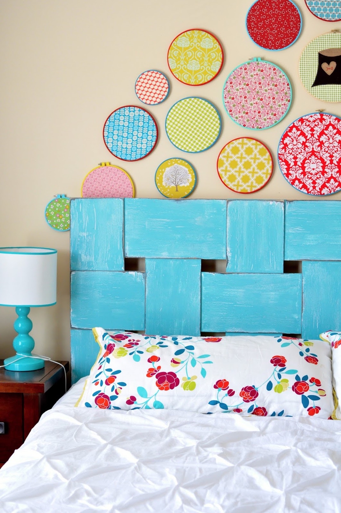 une chambre à coucher aux accents pop avec une tete de lit bois récup peinte en turquoise surmonté de cercles à broder détournés