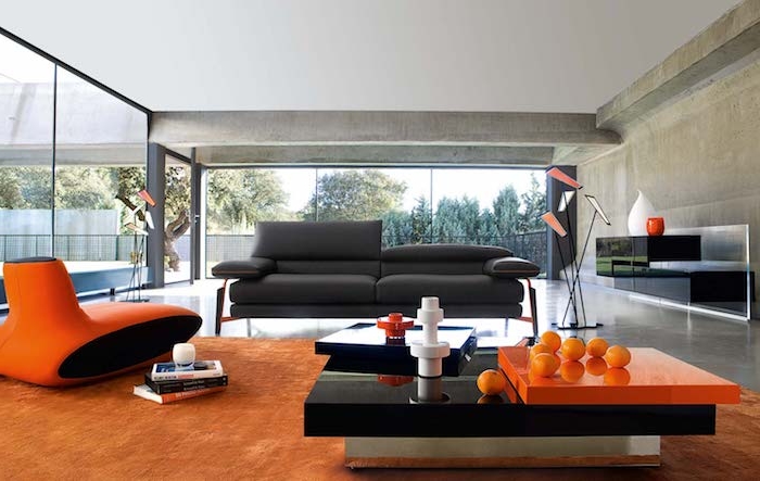 murs couleur taupe clair, tapis et fauteuil design couleur orange, table basse moderne noir et orange, canapé couleur gris anthracite