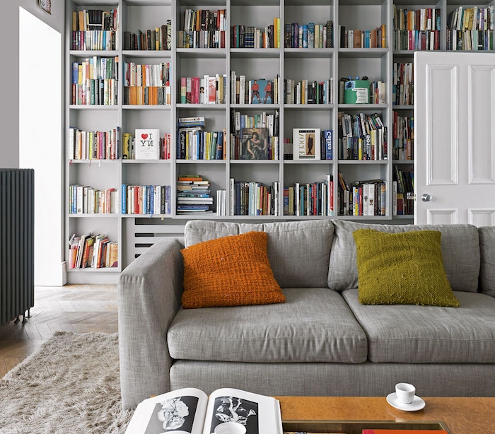 idée déco salon moderne avec frange bibliothèque grise coussin orange et vert, canapé gris perle, tapis gris moelleux, table basse en bois
