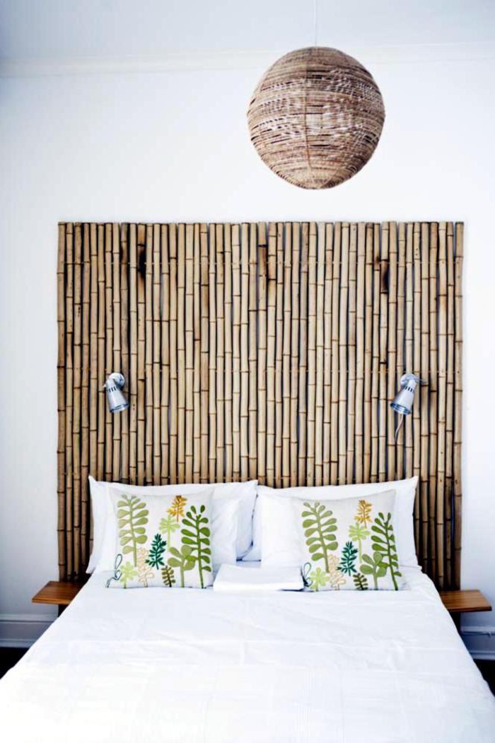 une chambre à coucher de style colonial avec tete de lit en bambou originale, une suspension en rotin et des motifs imprimés végétaux 