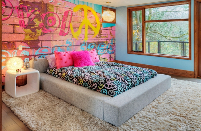 un papier peint mur en briques avec graffiti, lit plateforme gris, idée déco chambre parentale en rose et bleu, chevet blanc, encadrement de fenêtre bois foncé