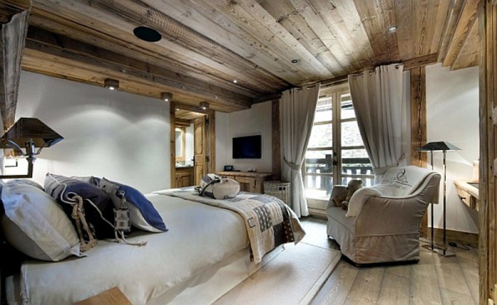 idée deco cocooning, intérieur de chalet rustique, fauteuil beige, murs peints blancs, plafond en bois
