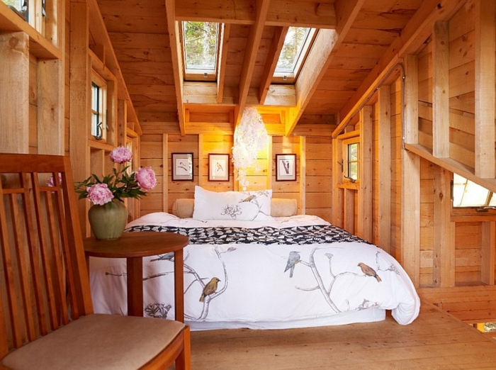 intérieur style cottage, lit sous les toits, banquette en bois et textile, vase avec des fleurs, lit sous la fenêtre