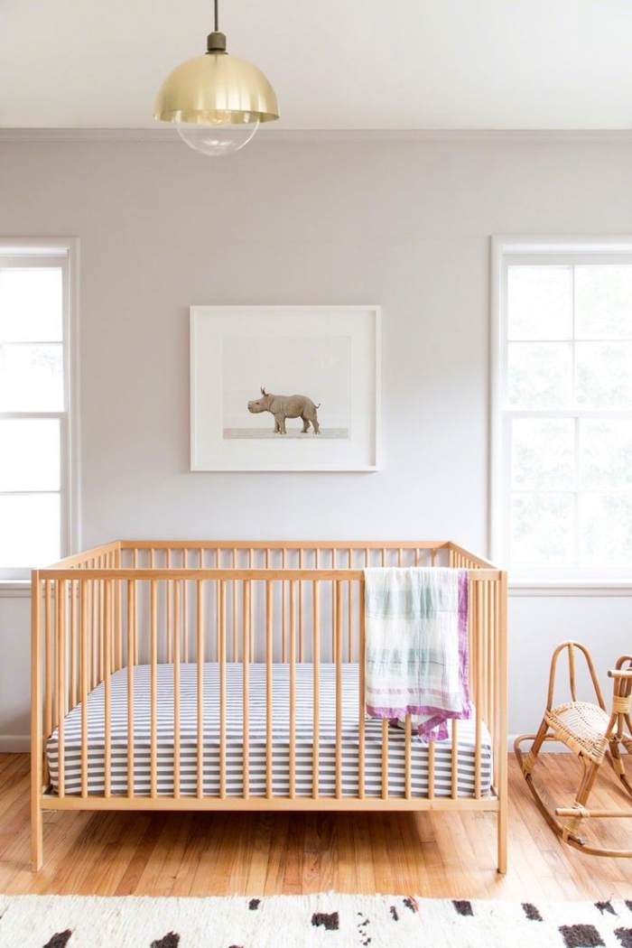 modèle de grand lit bebe fille ou garçon dans une chambre beige au plancher de bois clair avec tapis blanc et marron