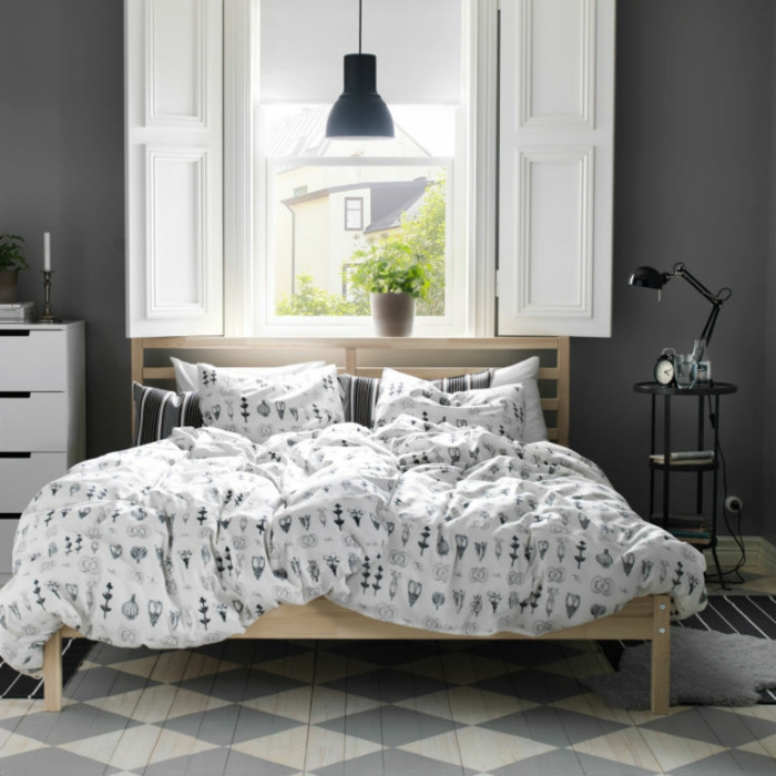 sol à patterns géométriques, linge de lit avec des motifs nordiques, lampe noire, fenêtre à volets blancs