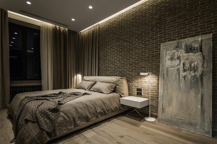 mur en briques, lit beige, petit chevet blanc, lampe de sol moderne, amenagement chambre minimaliste
