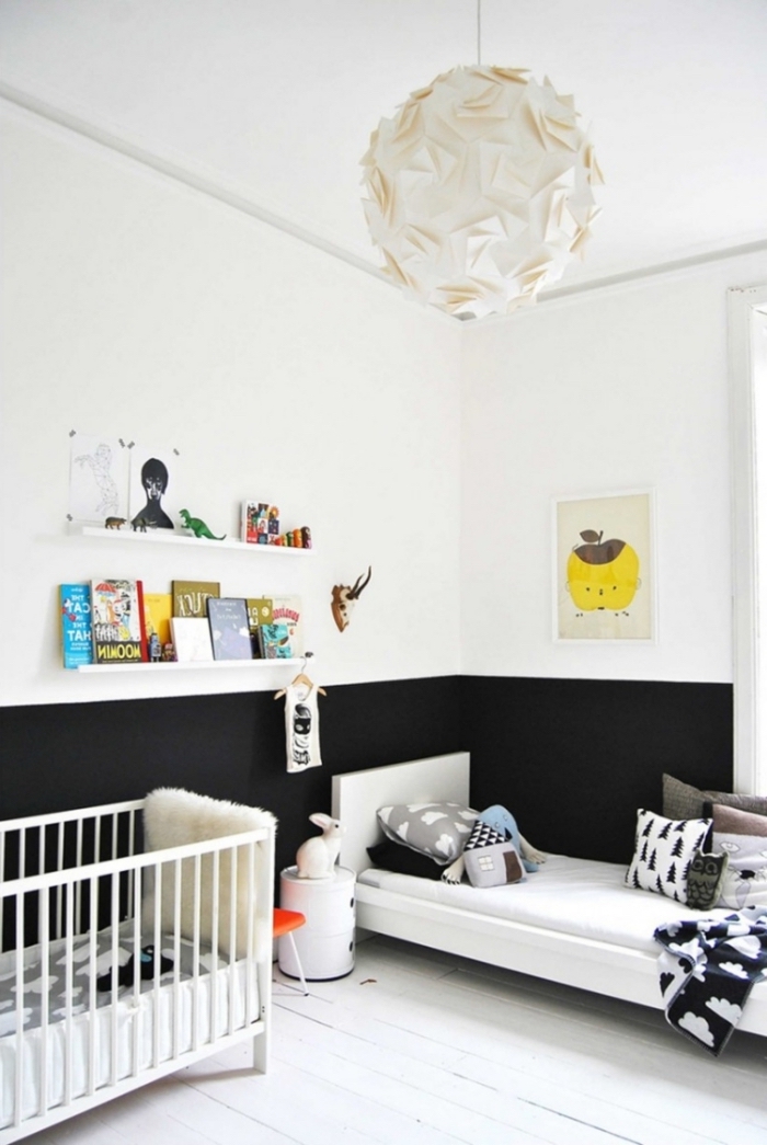 murs blanc et noir dans la chambre bébé fille avec lit blanc couvert de coussins décoratifs à imprimés scandinave